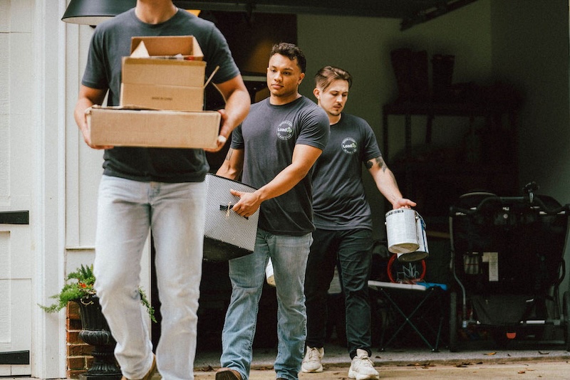 Three Loaders in the process of a property cleanout, emptying boxes and paint cans from a garage