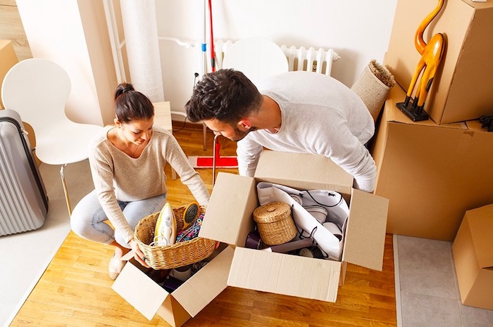 tips for moving on a budget two people lifting full cardboard moving boxes off floor