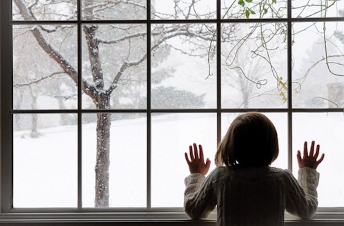 Little girl looking at snow outside window