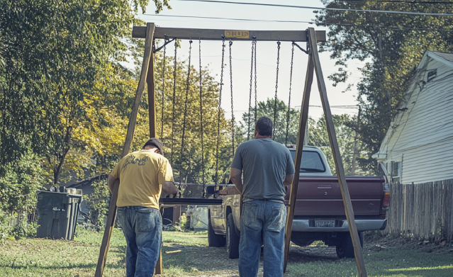 Junk removal professionals hauling away a swing set for a happy customer