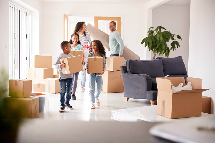 Family of a wife and husband and three children carrying moving boxing into their new home