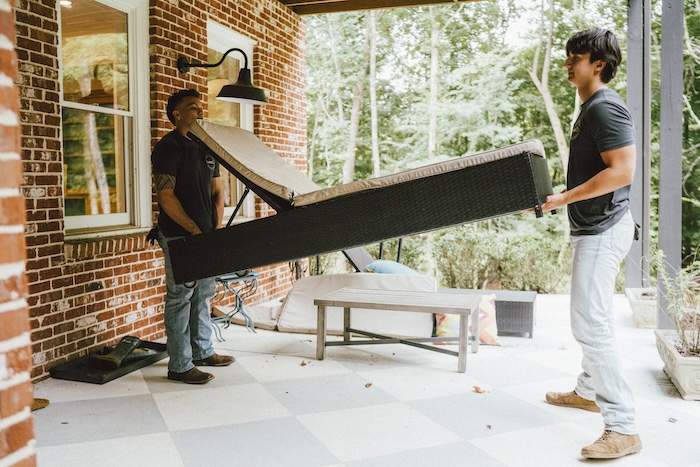 Two junk hauling professionals hauling away old broken furniture for outdoor pickup services