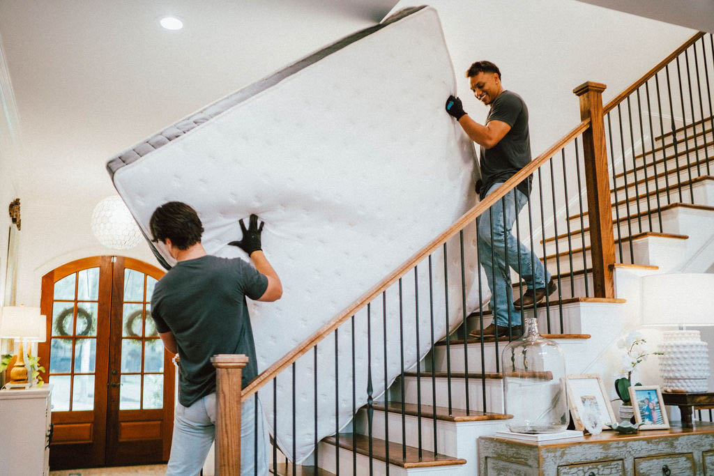 Two mattress professionals carrying a mattress