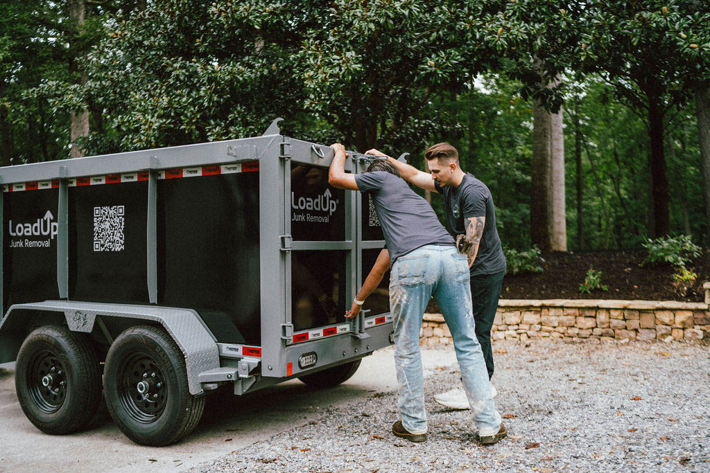 Two LoadUp junk haulers closing trailer after removing items for a customer