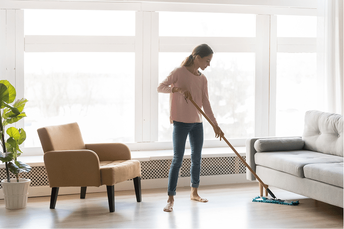 Woman mopping a bright living room during spring cleaning
