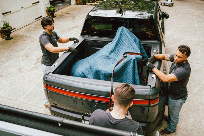 Three Loaders securing items in the back of their truck.